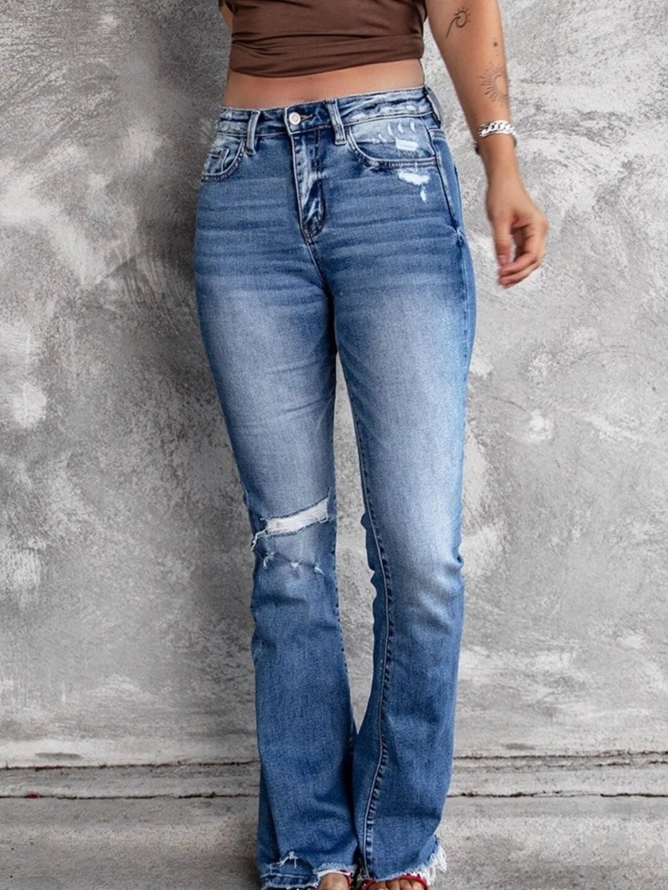 Light blue distressed flare jeans with ripped knees and faded whiskering on the legs