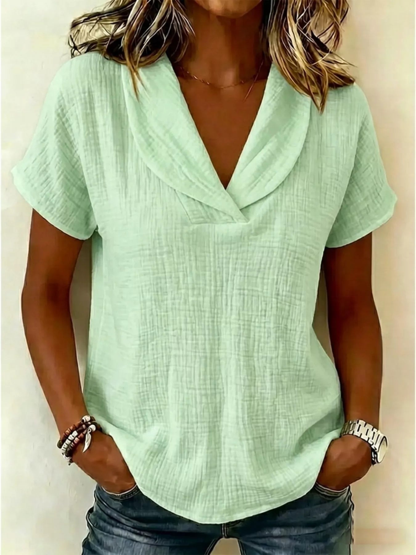 Textured short-sleeve blouse in light green, V-neck and draped collar.