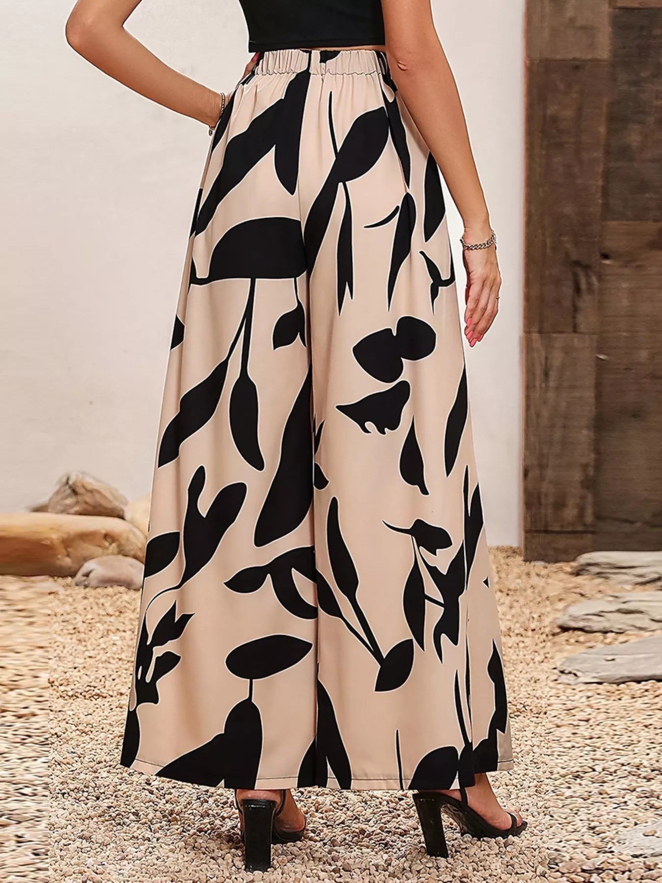 Printed wide-leg pants with elastic waistband, tan base and black botanical print.