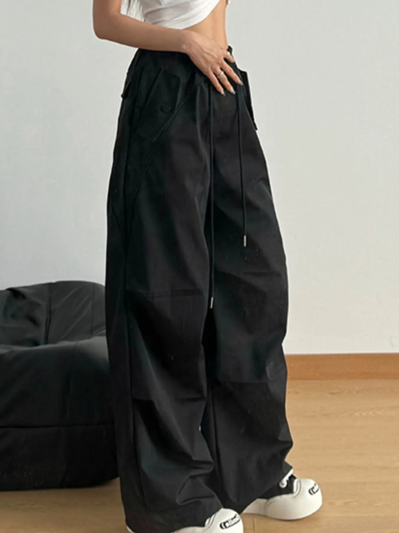 Black wide-leg drawstring pants with elastic waist, side pockets, and relaxed legs