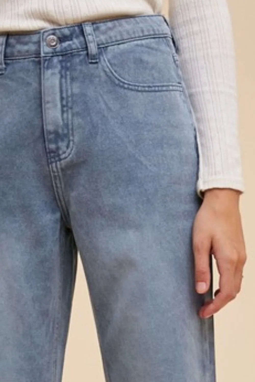 Dusty blue distressed jeans close-up with button fly, belt loops, and front pocket