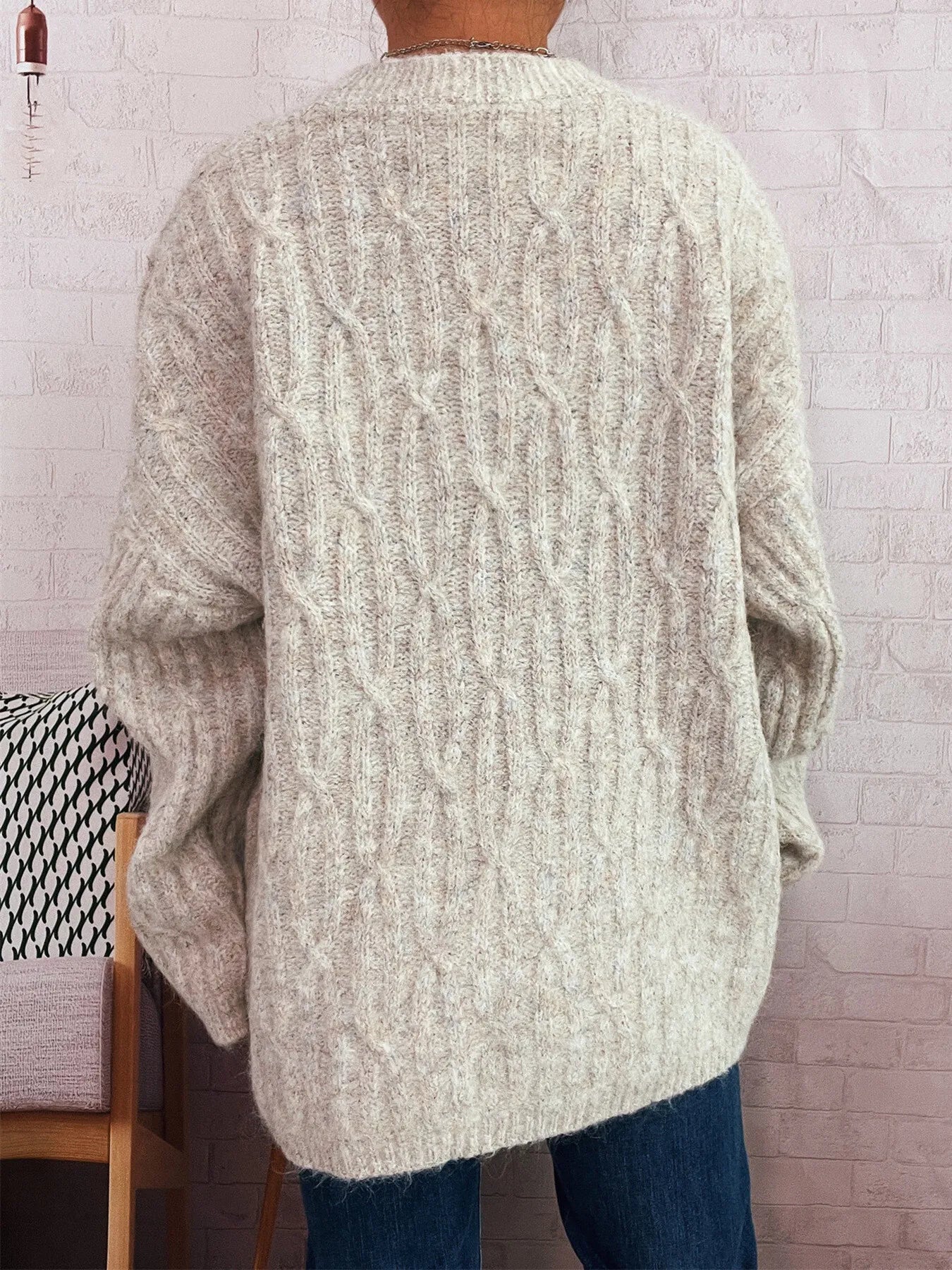 Cream cable knit cardigan from back view with full-length sleeves and ribbed hem