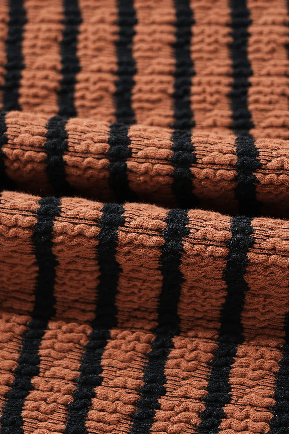 Close-up of caramel knit fabric with black vertical stripe texture