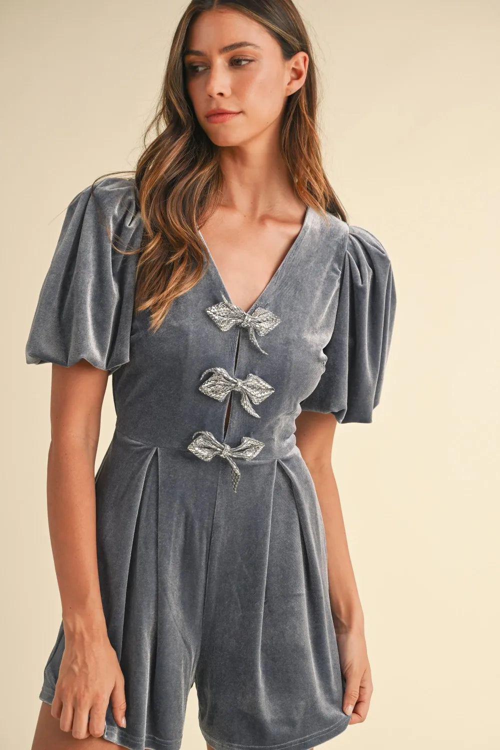 Dusty blue velvet romper close-up: V-neck with bow appliques and puff sleeves