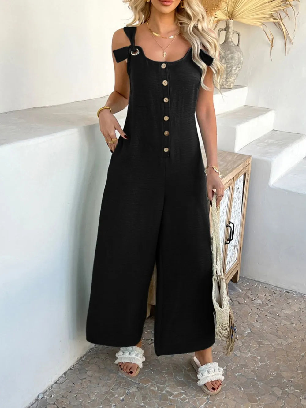 Black button-front wide-leg jumpsuit with square neckline and gold button placket