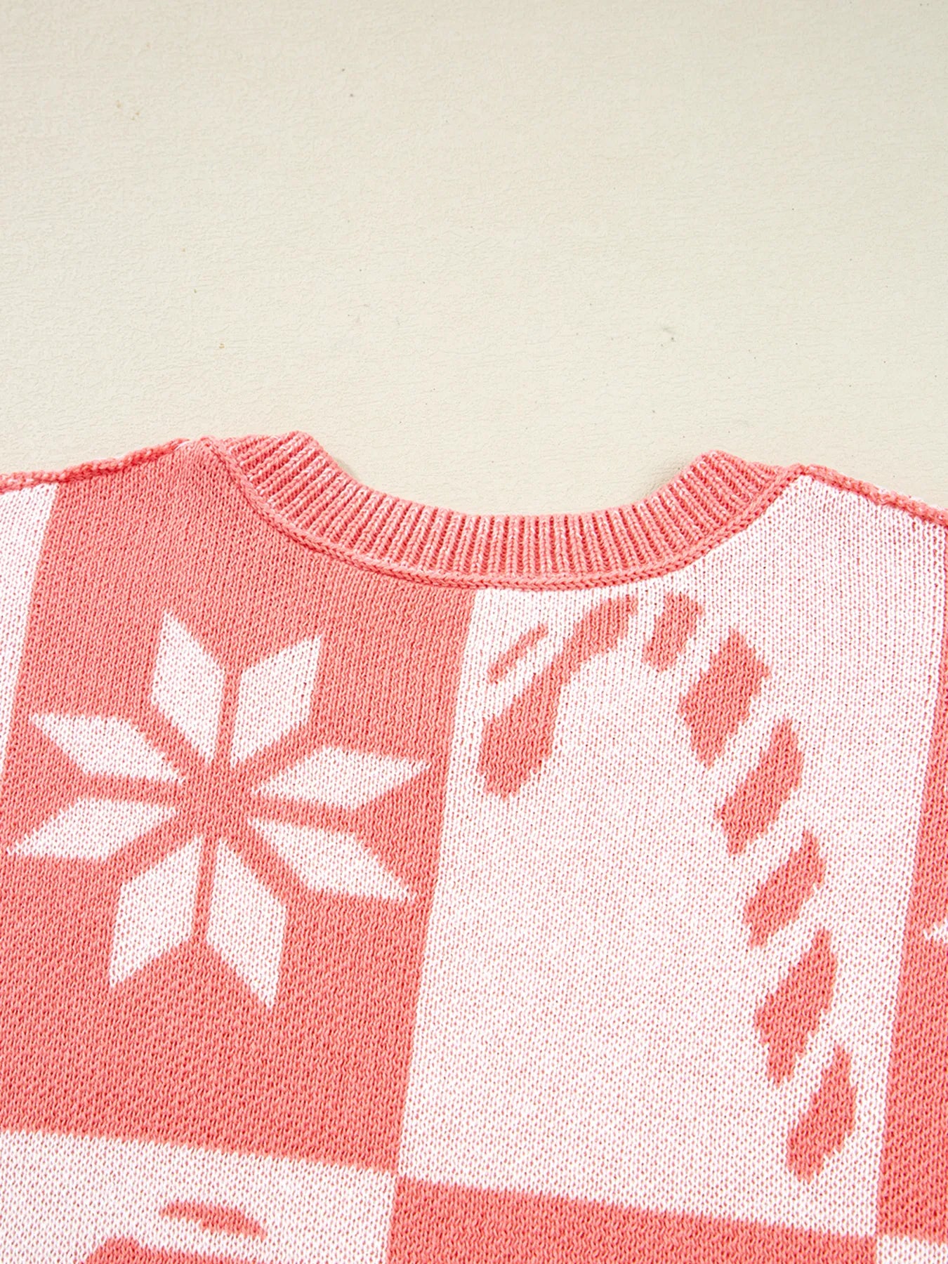 Burnt coral and white sweater with snowflake and candy-cane style icons in checker pattern