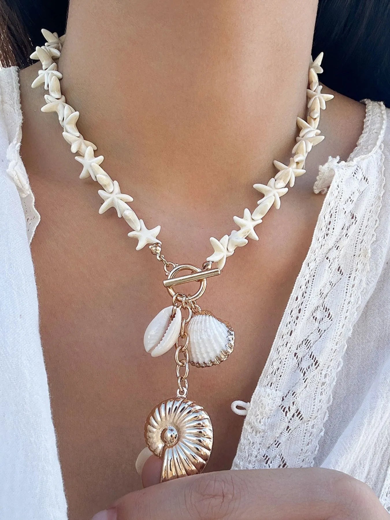 Gold shell necklace with starfish-shaped links, toggle clasp, and three shell charms