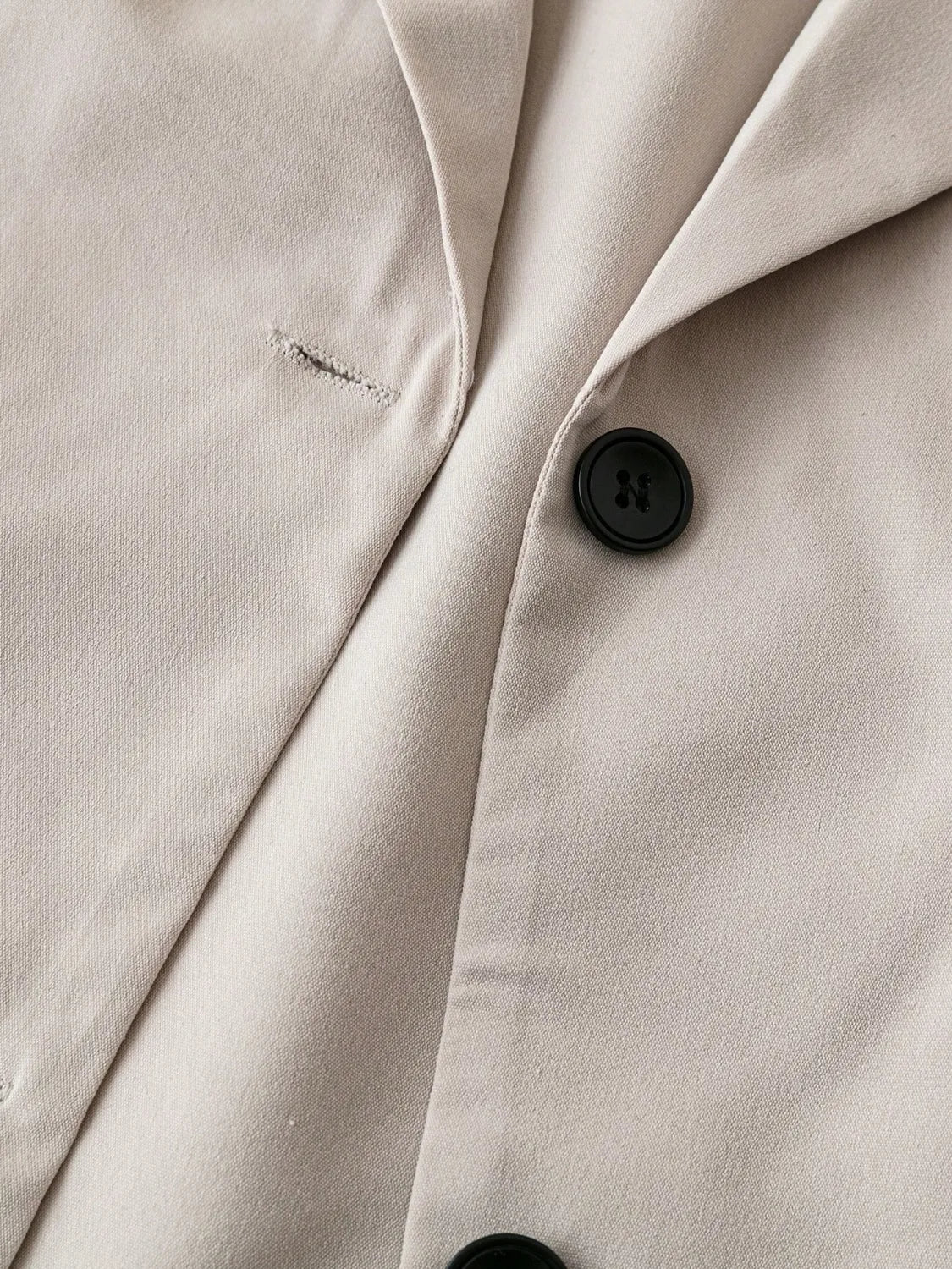 Light khaki blazer button placket and lapel seam close-up