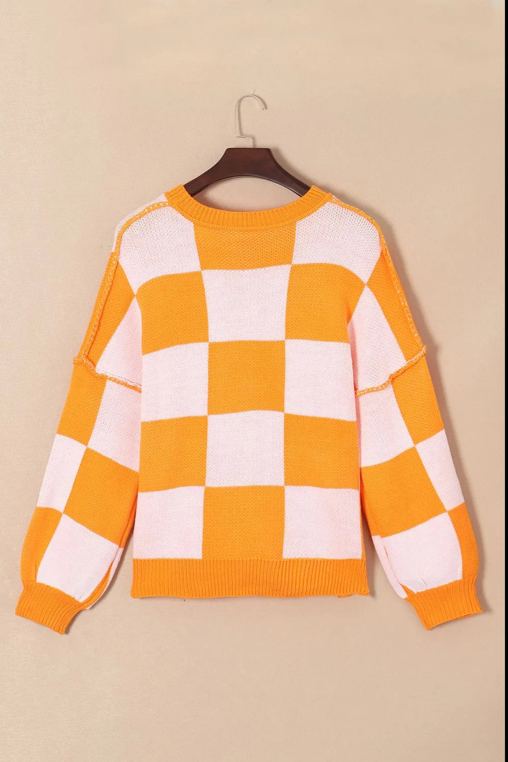Orange and white checkered knit sweater with ribbed crew neckline and cuffs on hanger