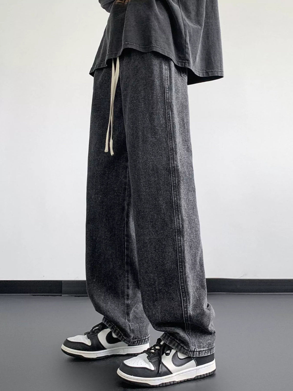 Dark gray washed denim jeans with loose fit, wide leg silhouette, and hanging ties