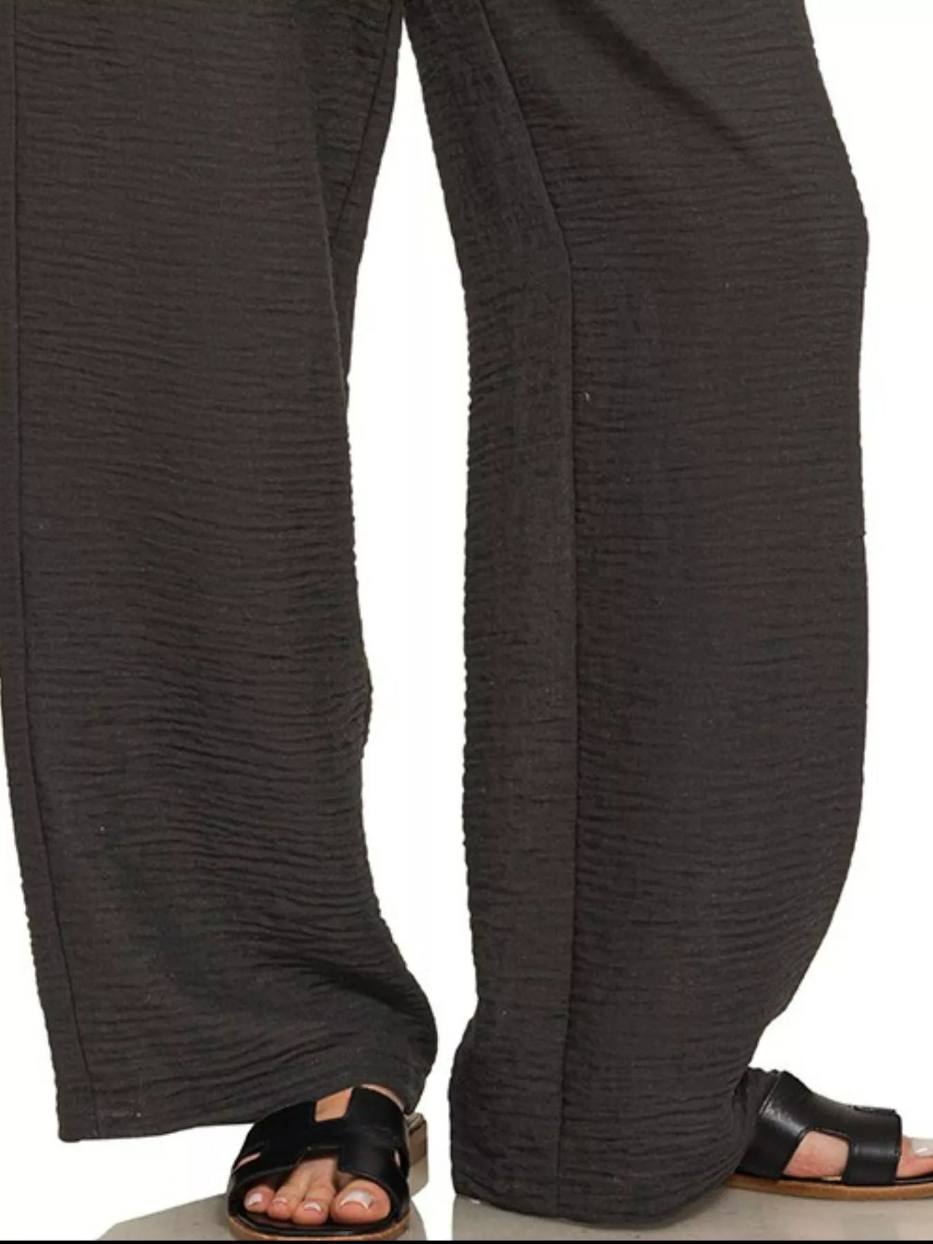 Black woven crepe pants with relaxed wide-leg fit and ankle-length cuff detail