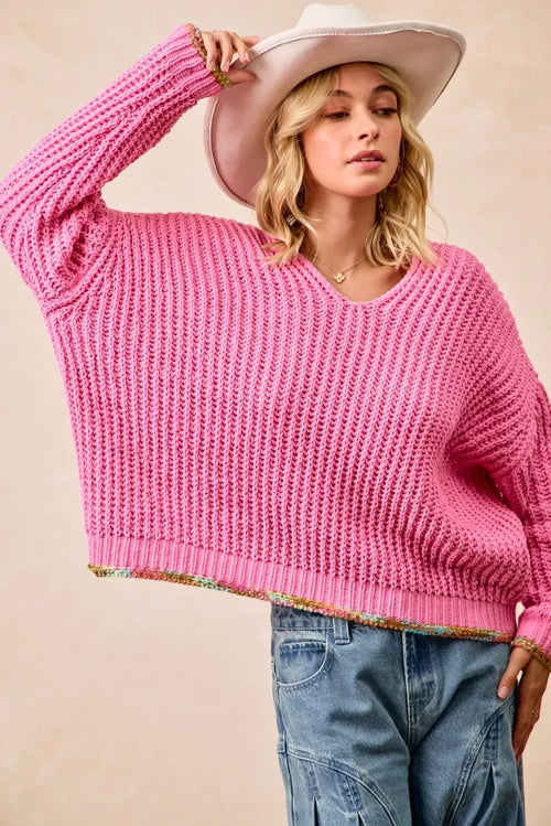 Women’s pink V-neck knit sweater, long sleeves; ribbed hem with colorful trim.