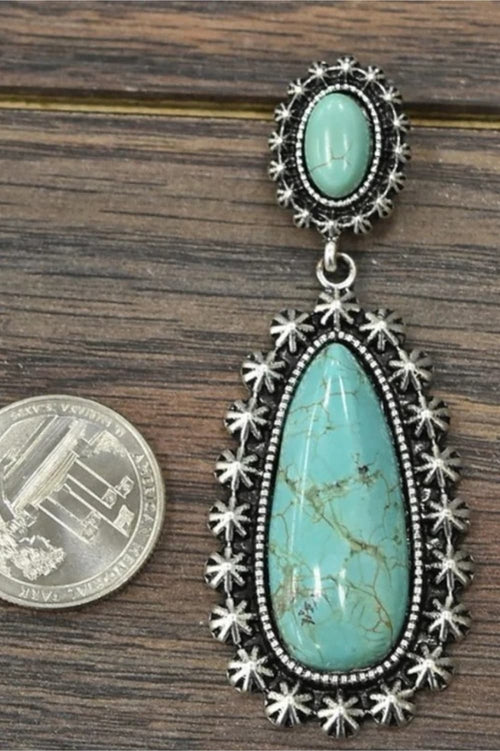 Turquoise oval-and-teardrop earrings with ornate starburst silver-tone frames