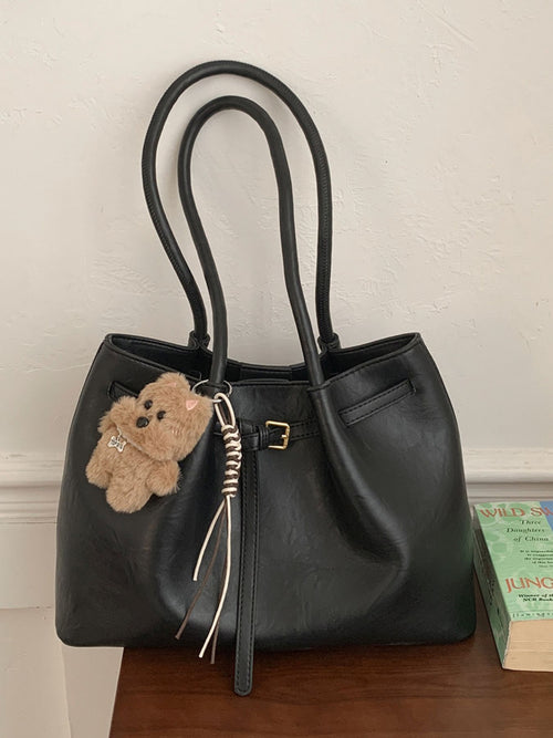 Black leather shoulder bag with buckle detail and teddy charm keychain