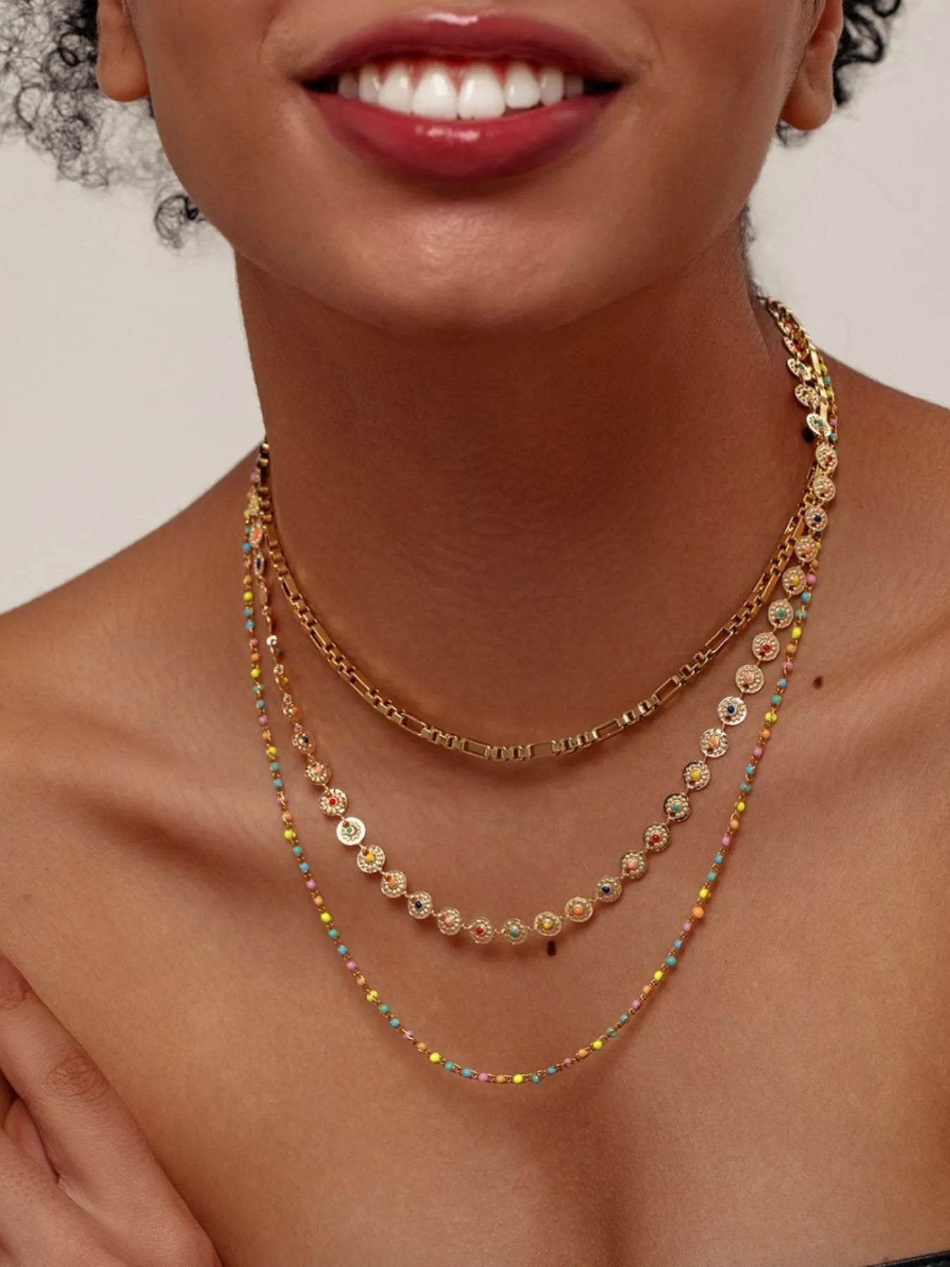 Gold-plated layered bead necklace with oval resin beads and thin multicolor tassel strands