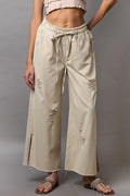 Cream distressed wide-leg drawstring pants with side slit and frayed hem