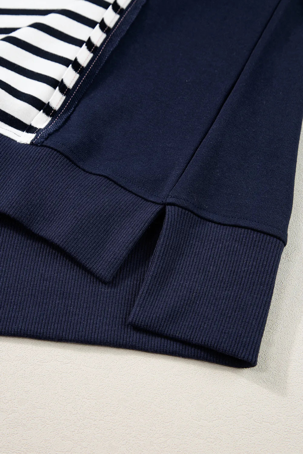 Ribbed navy sweatshirt hem with striped sleeve cuff and stitched seam detail