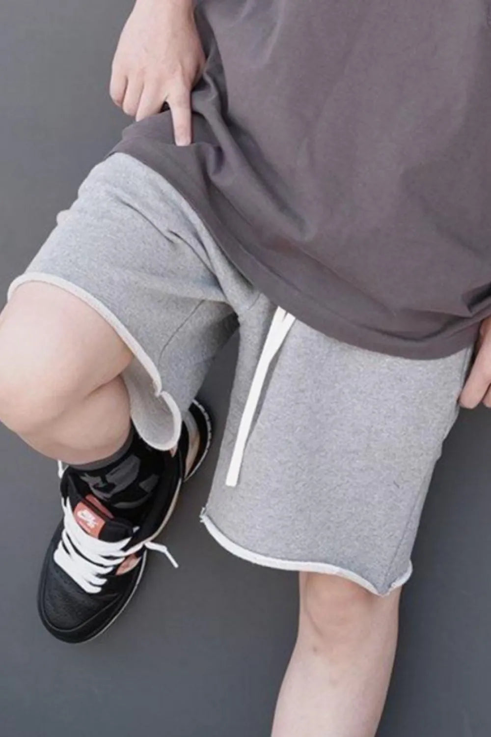 Gray drawstring shorts with elastic waist, visible drawcord ties, above-knee hem.