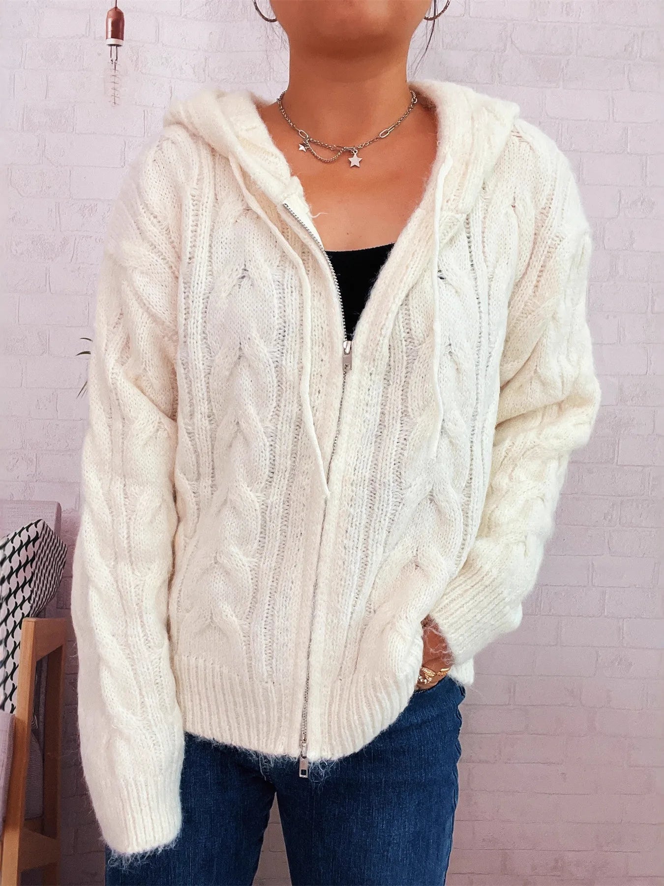 Cream cable knit hooded zip-up cardigan with front zipper and long sleeves, ribbed trim.