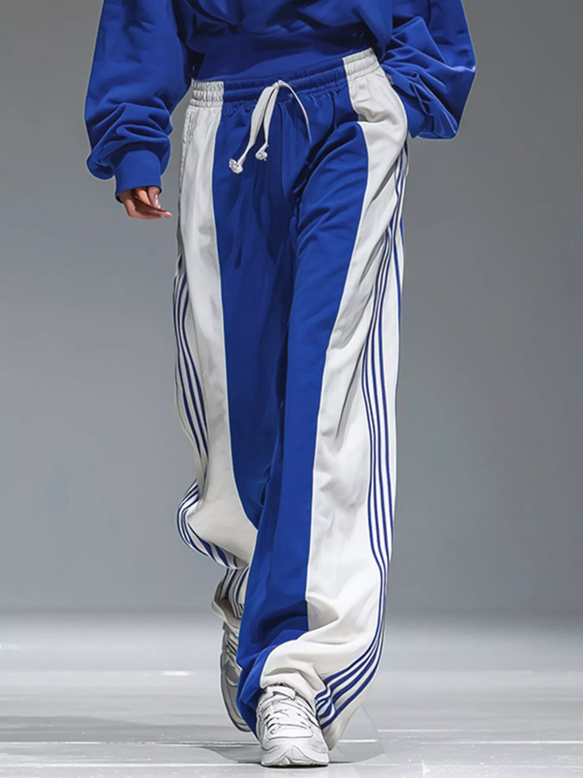 Blue hoodie and white-paneled wide-leg pants with vertical stripe seams and drawstring waist