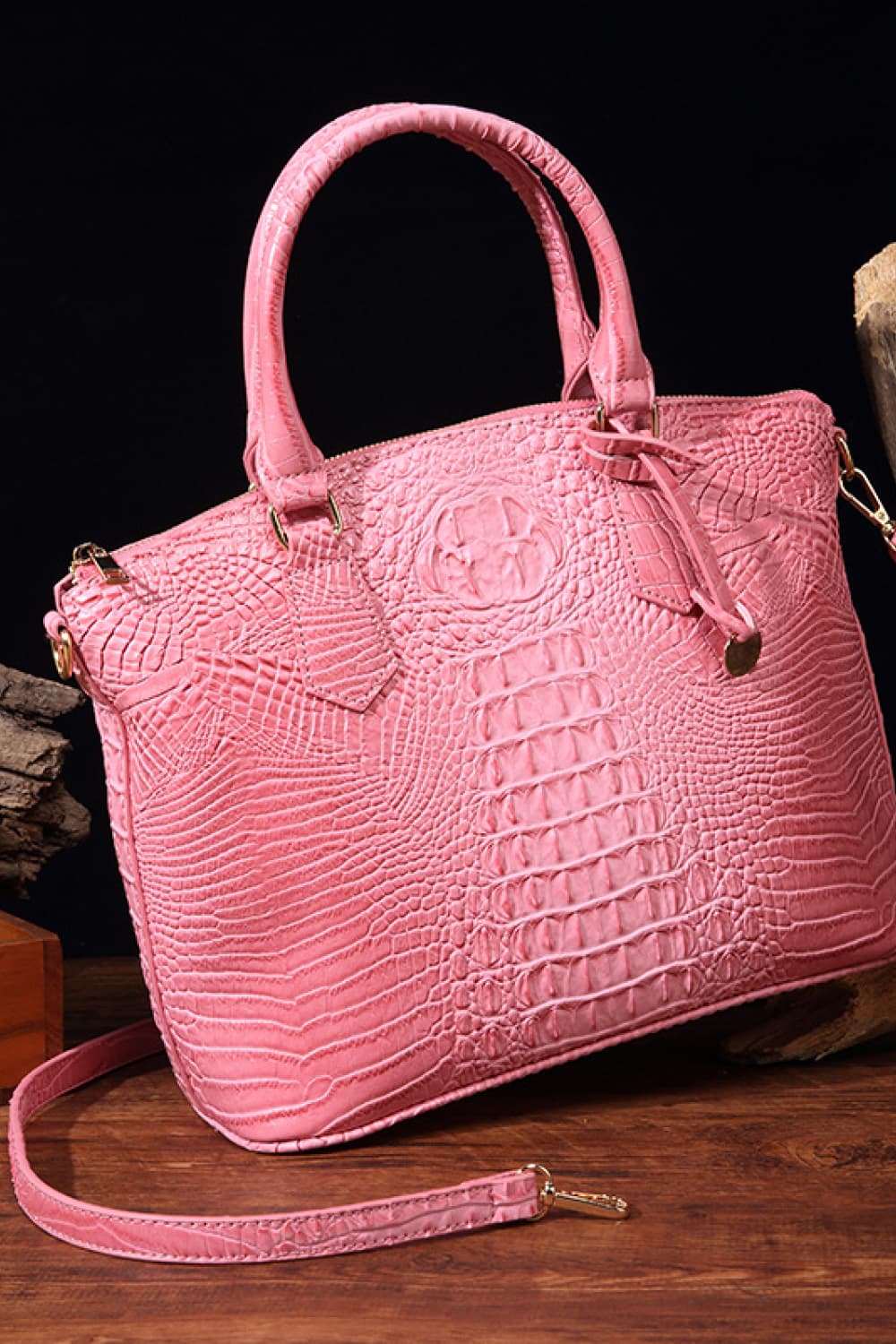 Vegan leather handbag in pink with top handles, embossed crocodile texture, and side strap