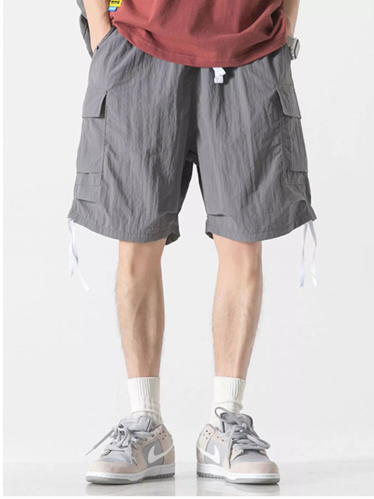 Gray cargo shorts with side pockets and drawstring ties, knee length