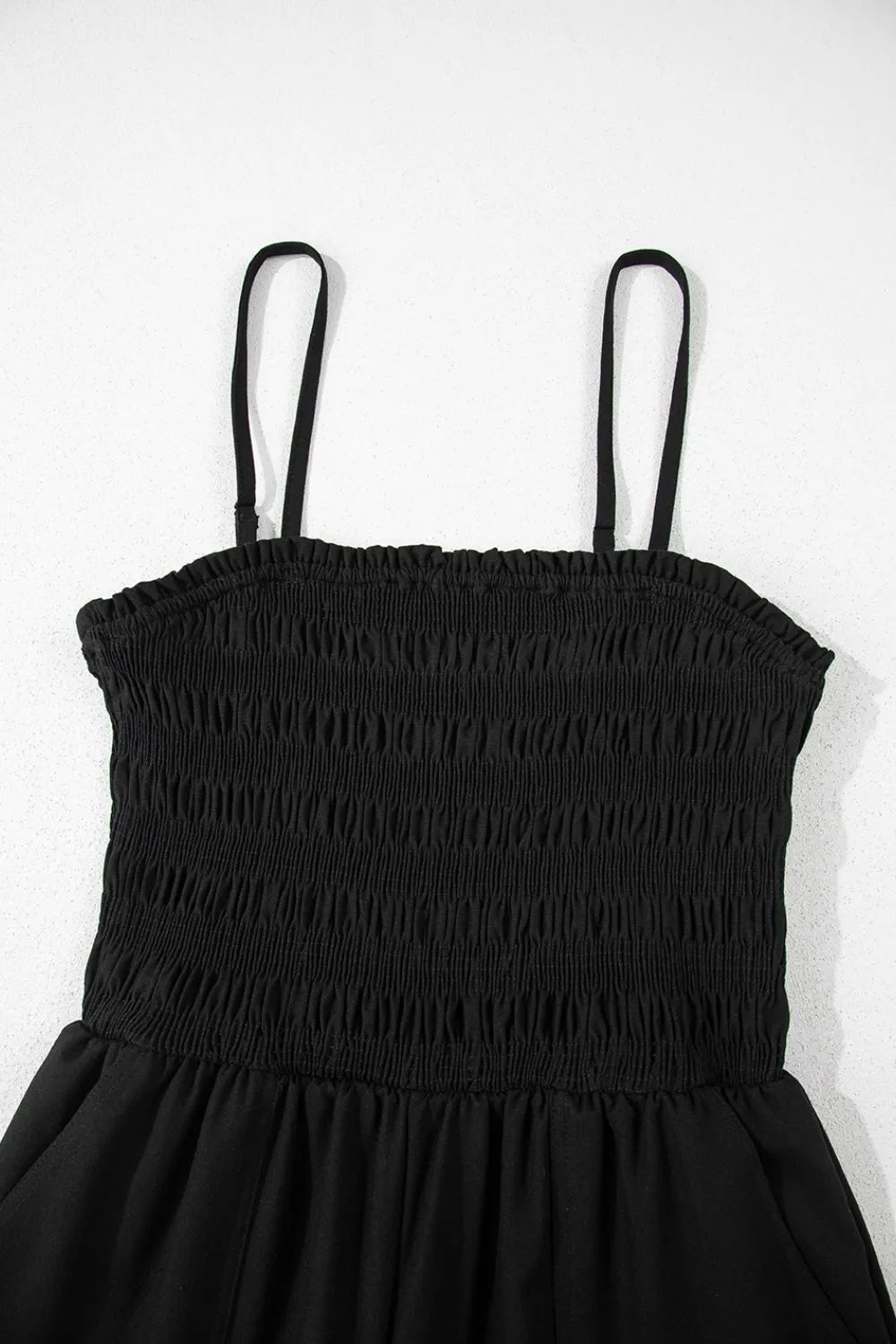 Black smocked spaghetti strap wide-leg jumpsuit neckline and gathered bust detail