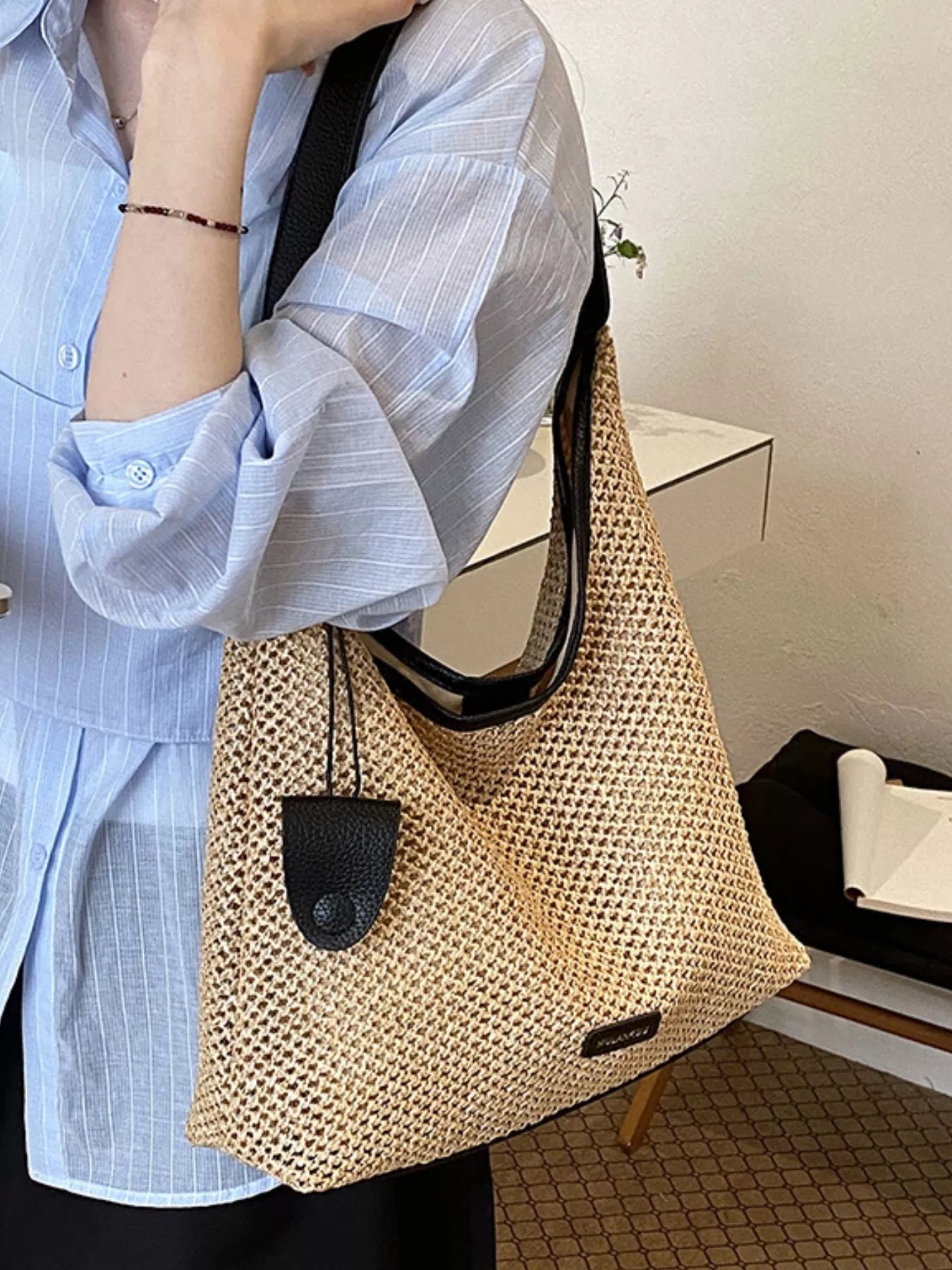 Camel woven straw shoulder bag with black front pocket and curved handle opening