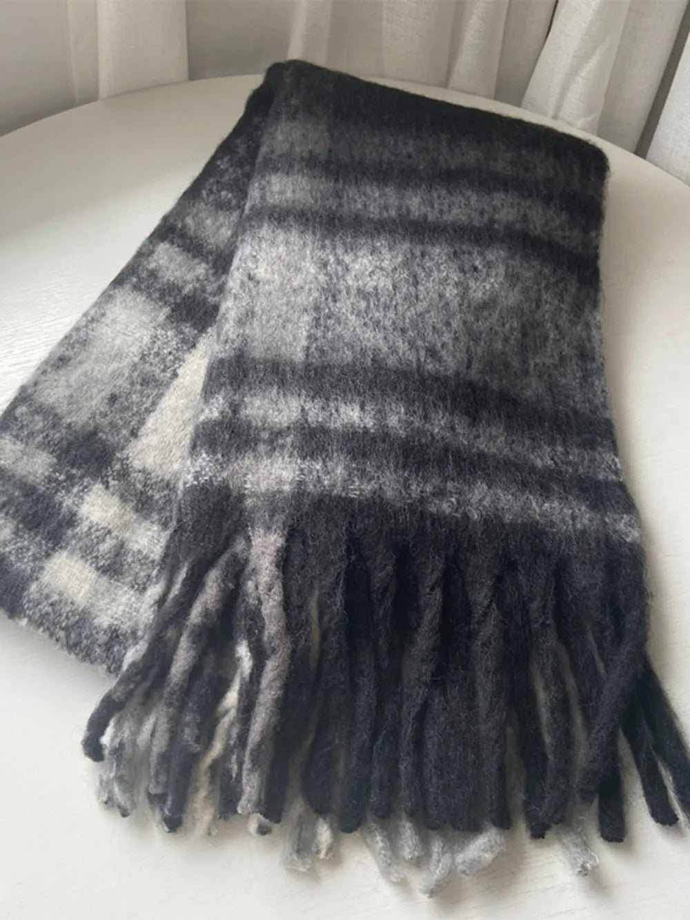 Plaid polyester scarf in dark gray and light gray with fringe trim.