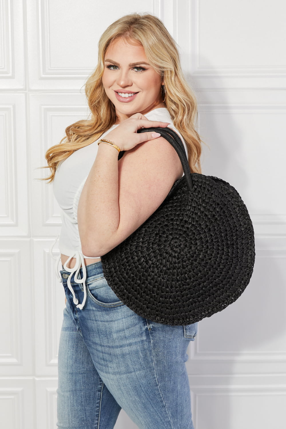 Black round woven straw rattan handbag with top handles, side view, open top