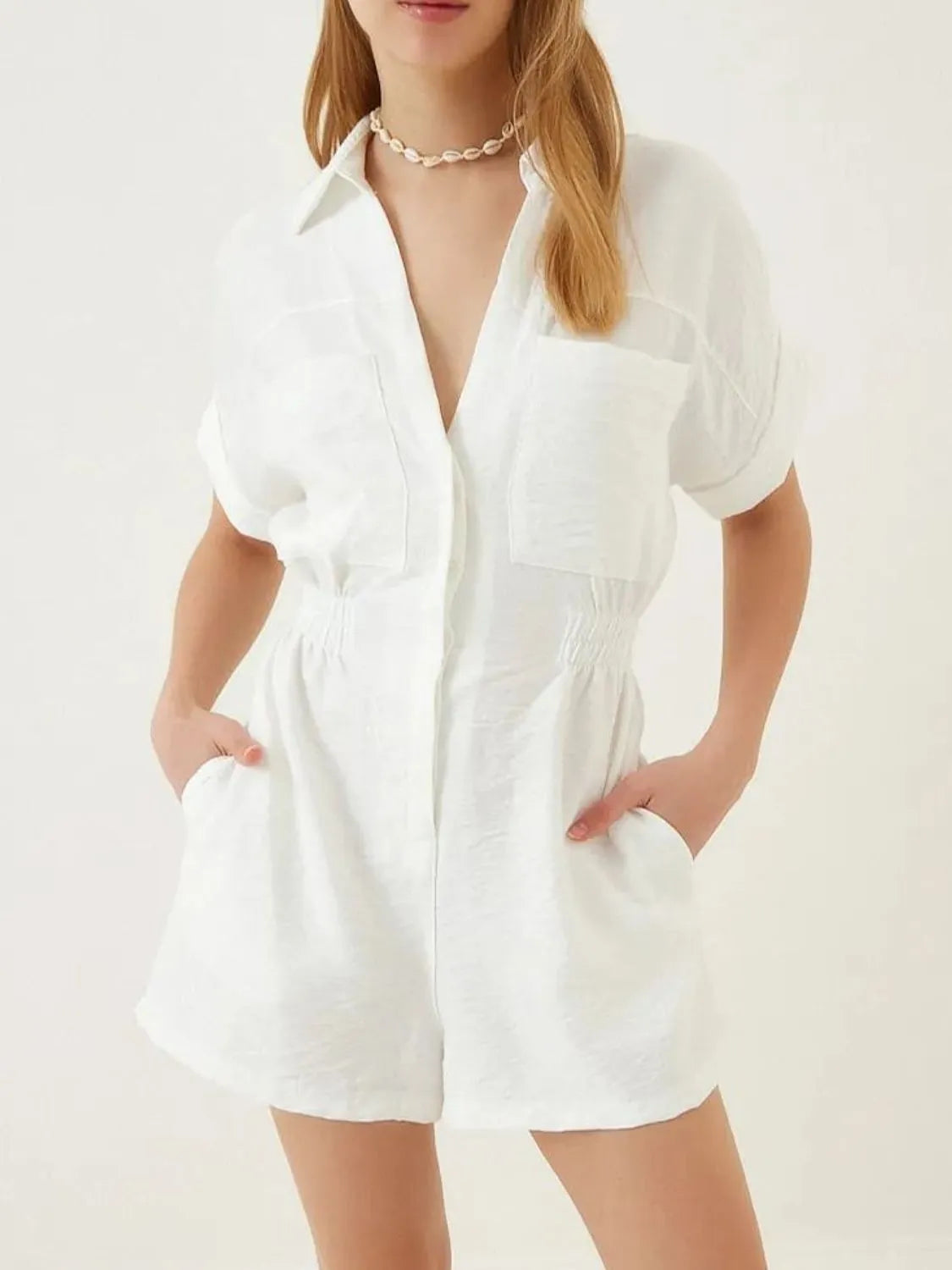 White short-sleeve romper with collar, button front, patch pockets, and elastic waist.