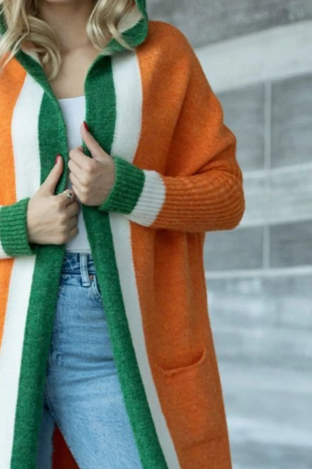 Orange hooded cardigan close-up with green-and-white striped contrast trim