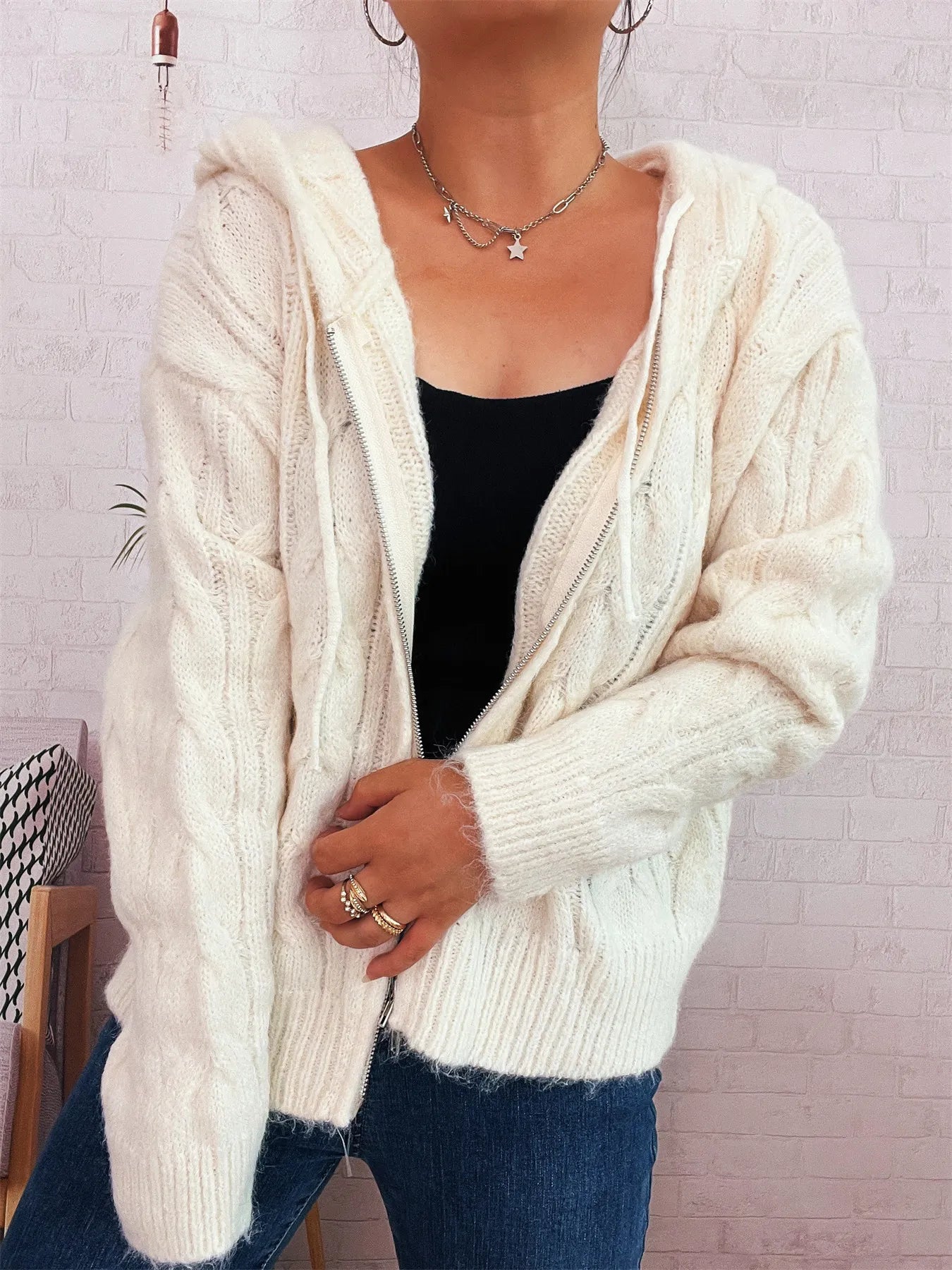 Cream hooded cable knit zip-up cardigan with front zipper and long sleeves, textured knit.