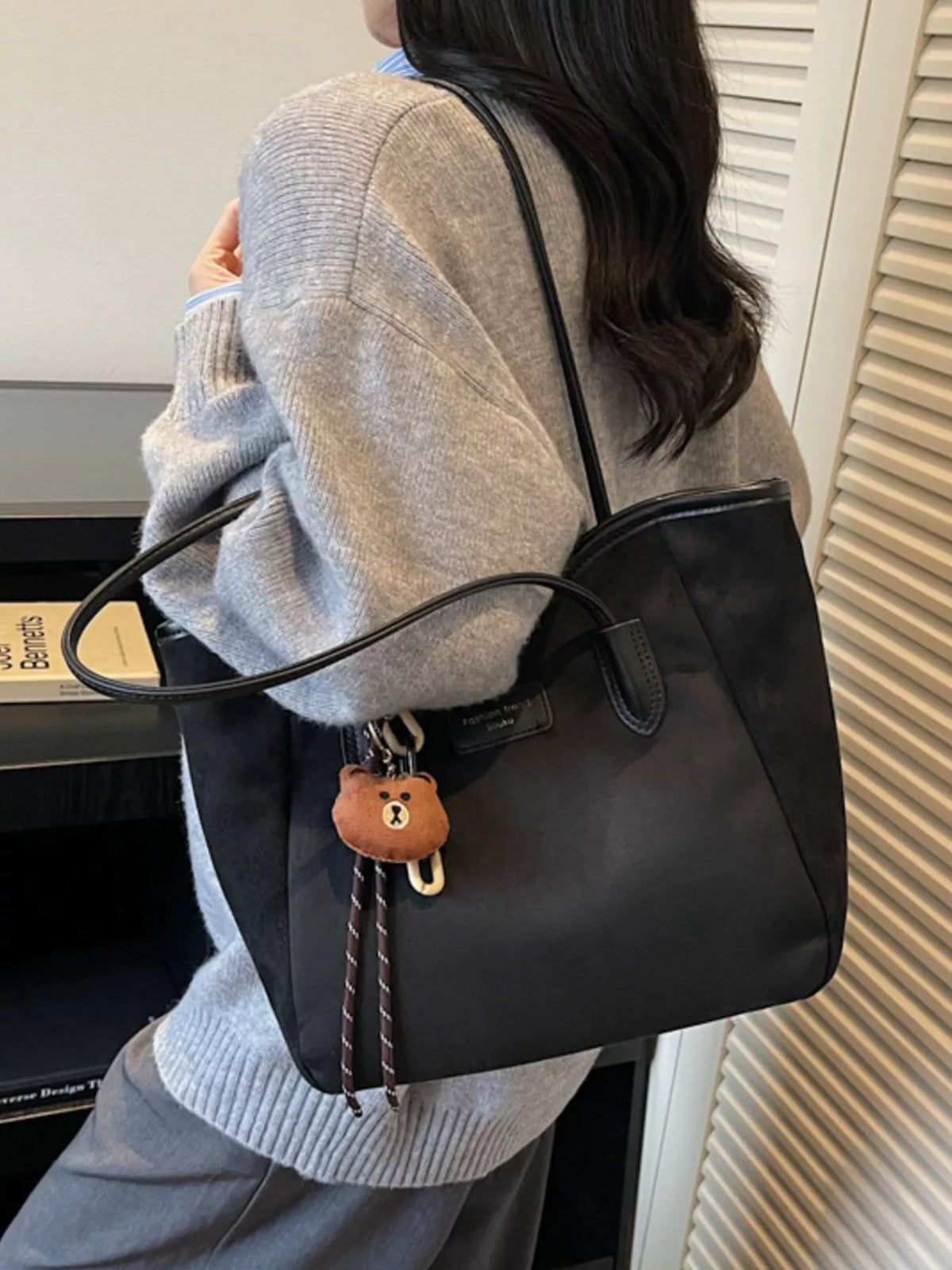 Black suede tote bag with long shoulder straps and bear keychain charm
