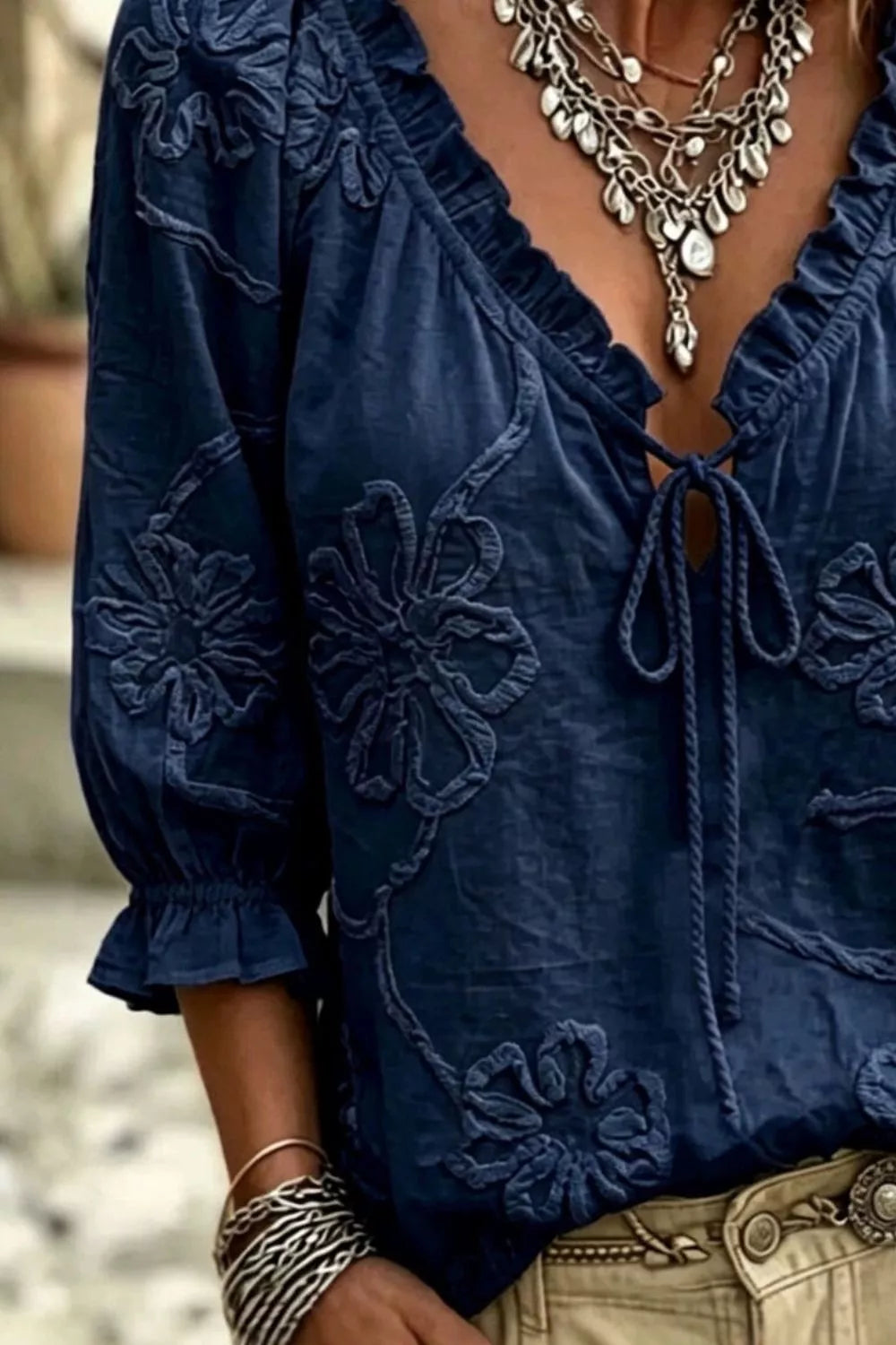Navy floral embroidered blouse with tie-neck front and ruffled sleeve cuffs
