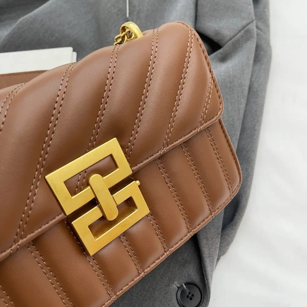 Brown quilted crossbody bag detail with gold G-style logo clasp and stitched panels.