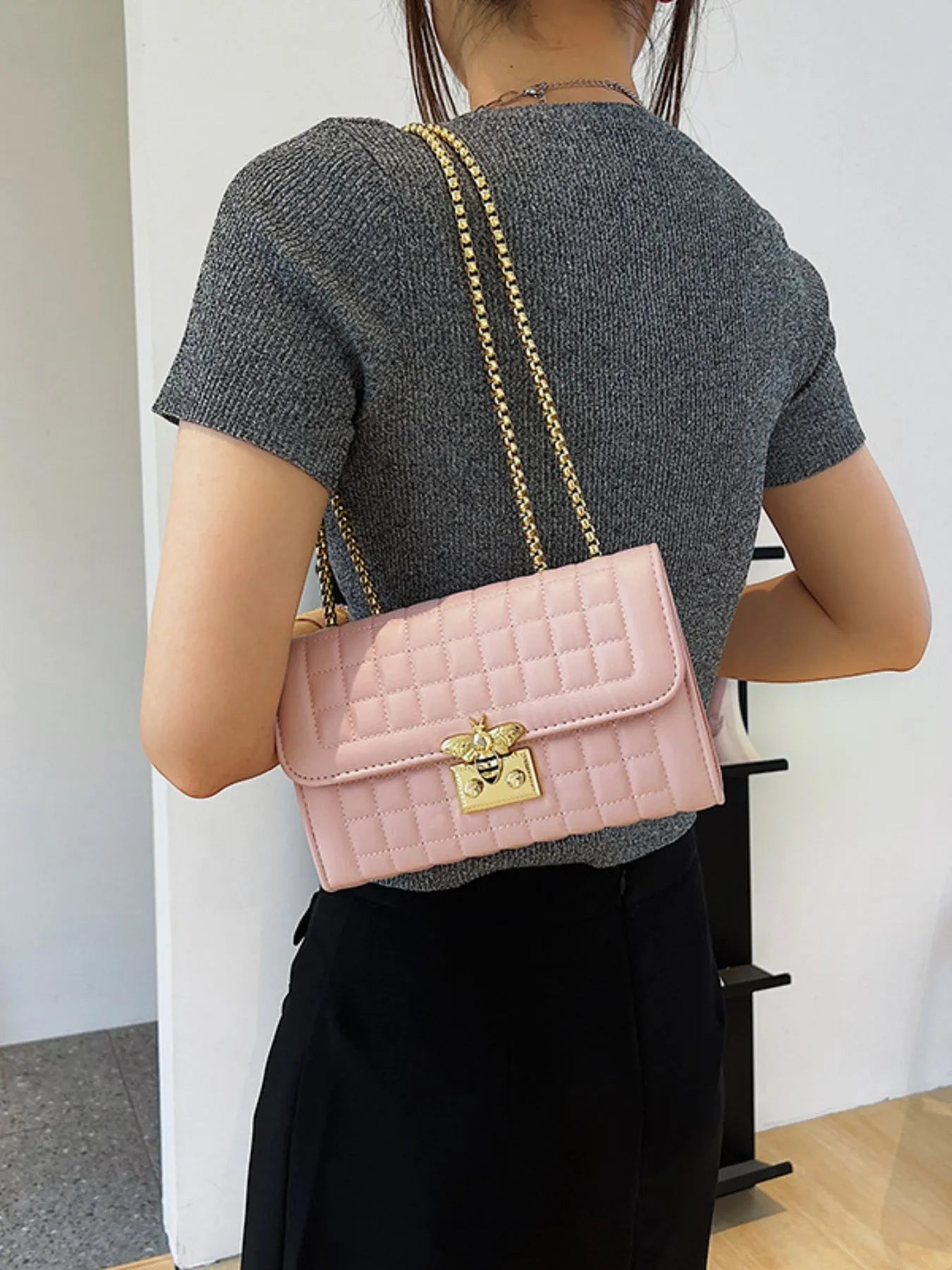 Pink quilted shoulder bag with gold chain strap, bee charm clasp, flap front