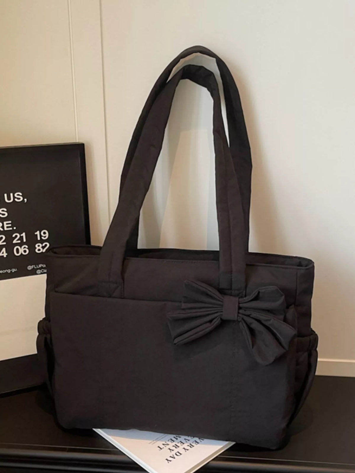 Black medium casual tote bag with front bow accent and wide handles