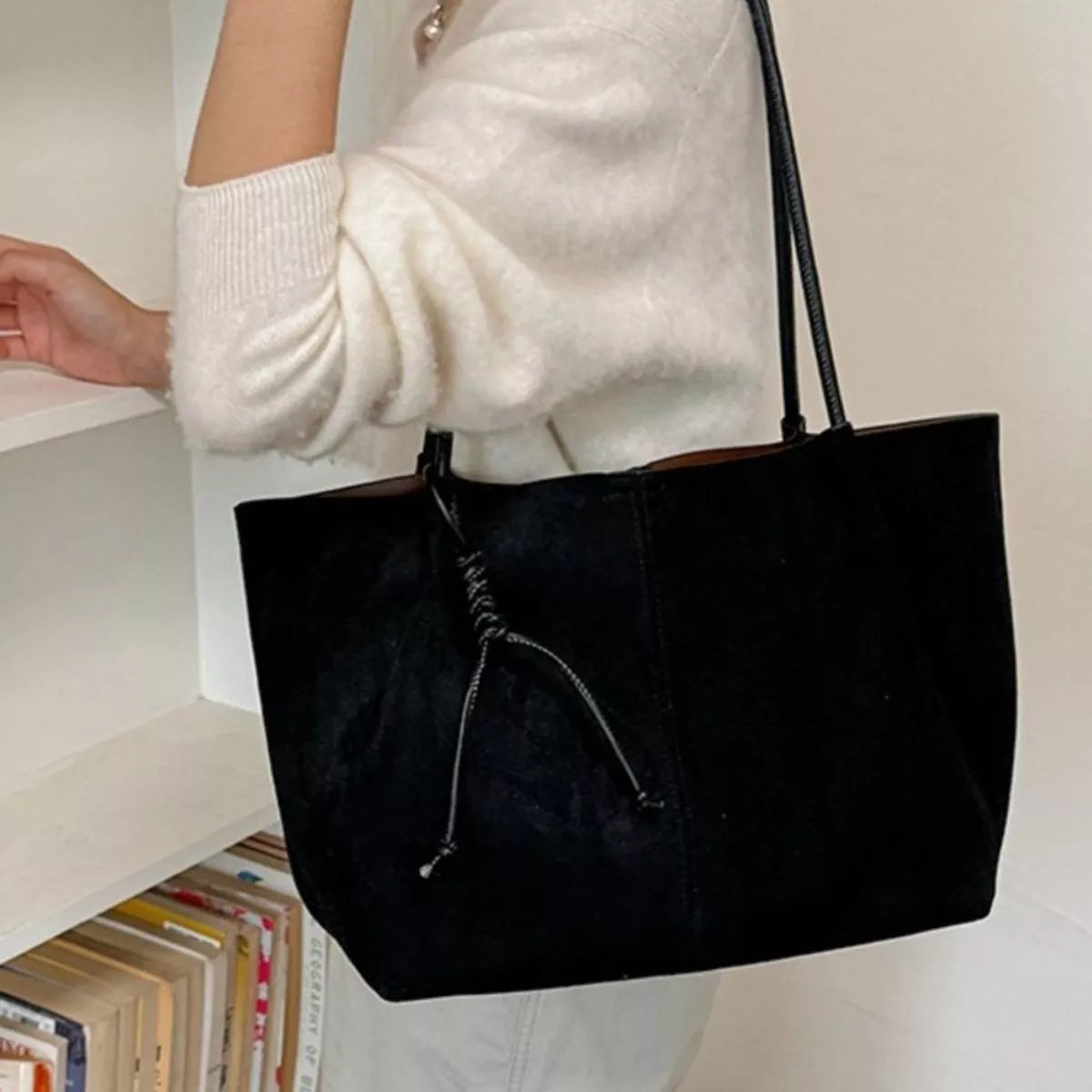 Black suede tote bag front view with drawstring pocket and two top handles