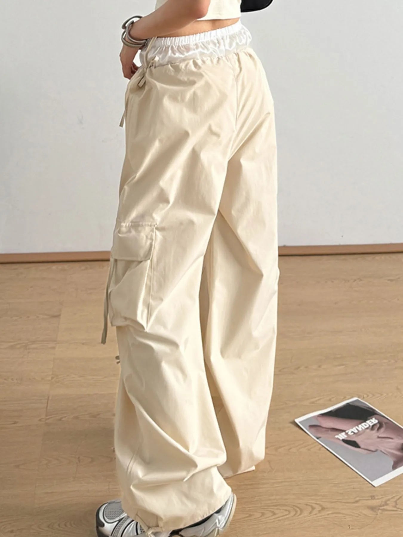 Tan wide-leg cargo pants with elastic waistband and side tie accents