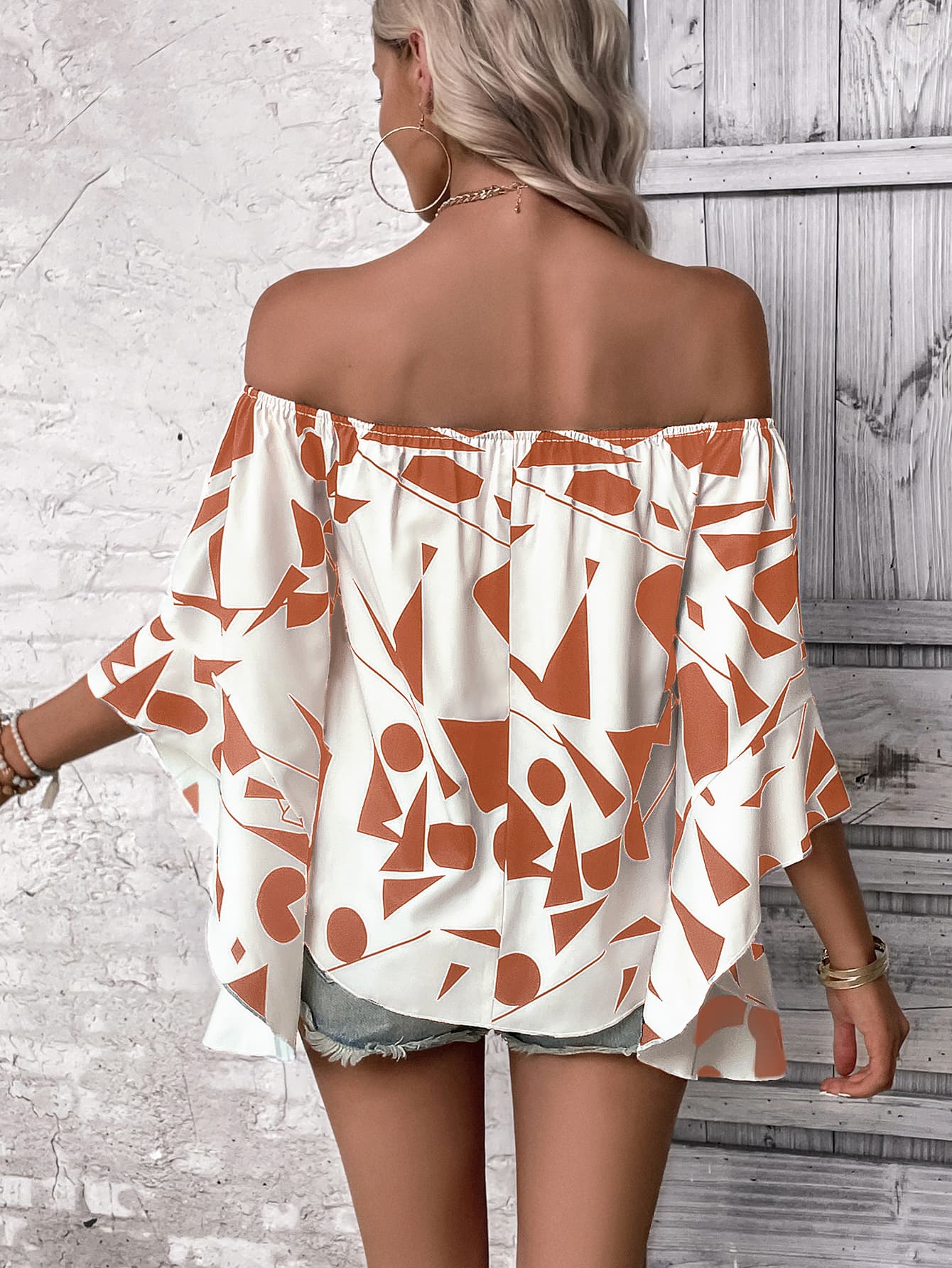 Back of off-shoulder bell sleeve blouse in white with orange abstract print