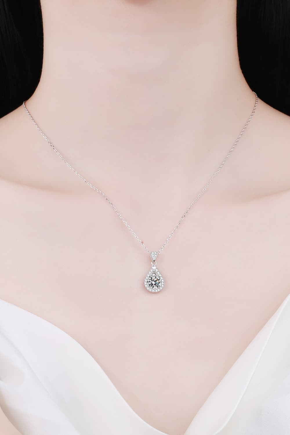 Sterling silver moissanite teardrop pendant necklace on a bare neckline