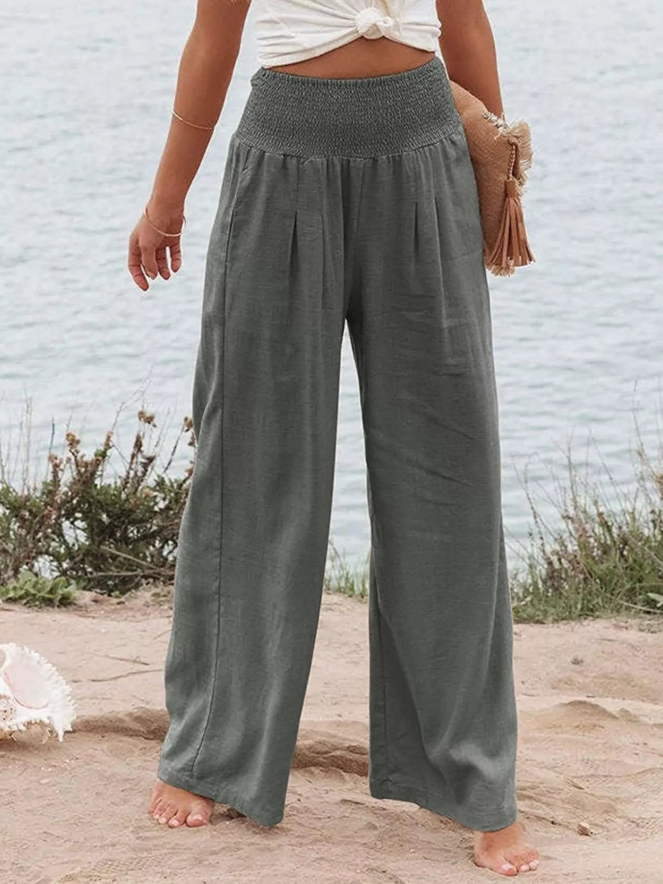 Dark gray smocked high-waist wide-leg pants with gathered waistband detail.
