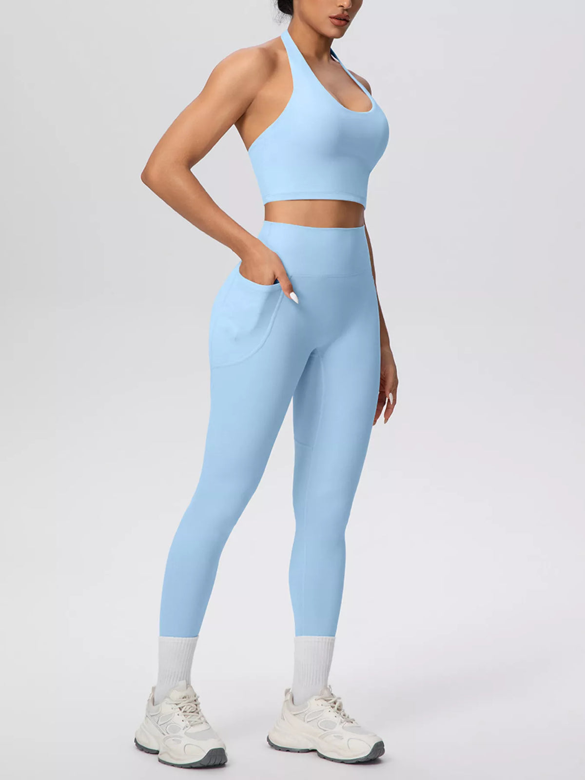 Dusty blue halter crop top and high-waist pocketed leggings, side view, full-length