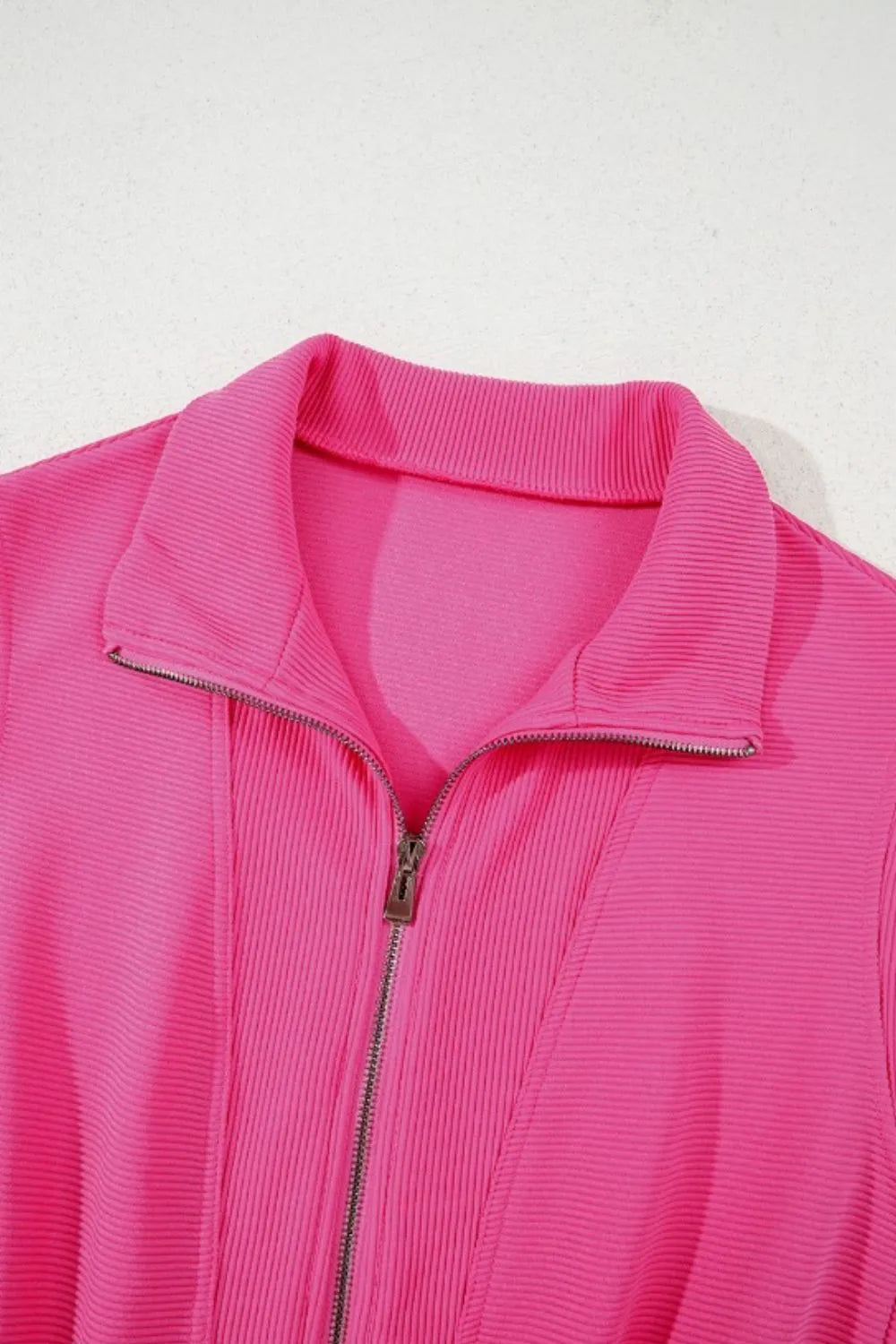 Hot pink textured half-zip romper collar and front placket close-up