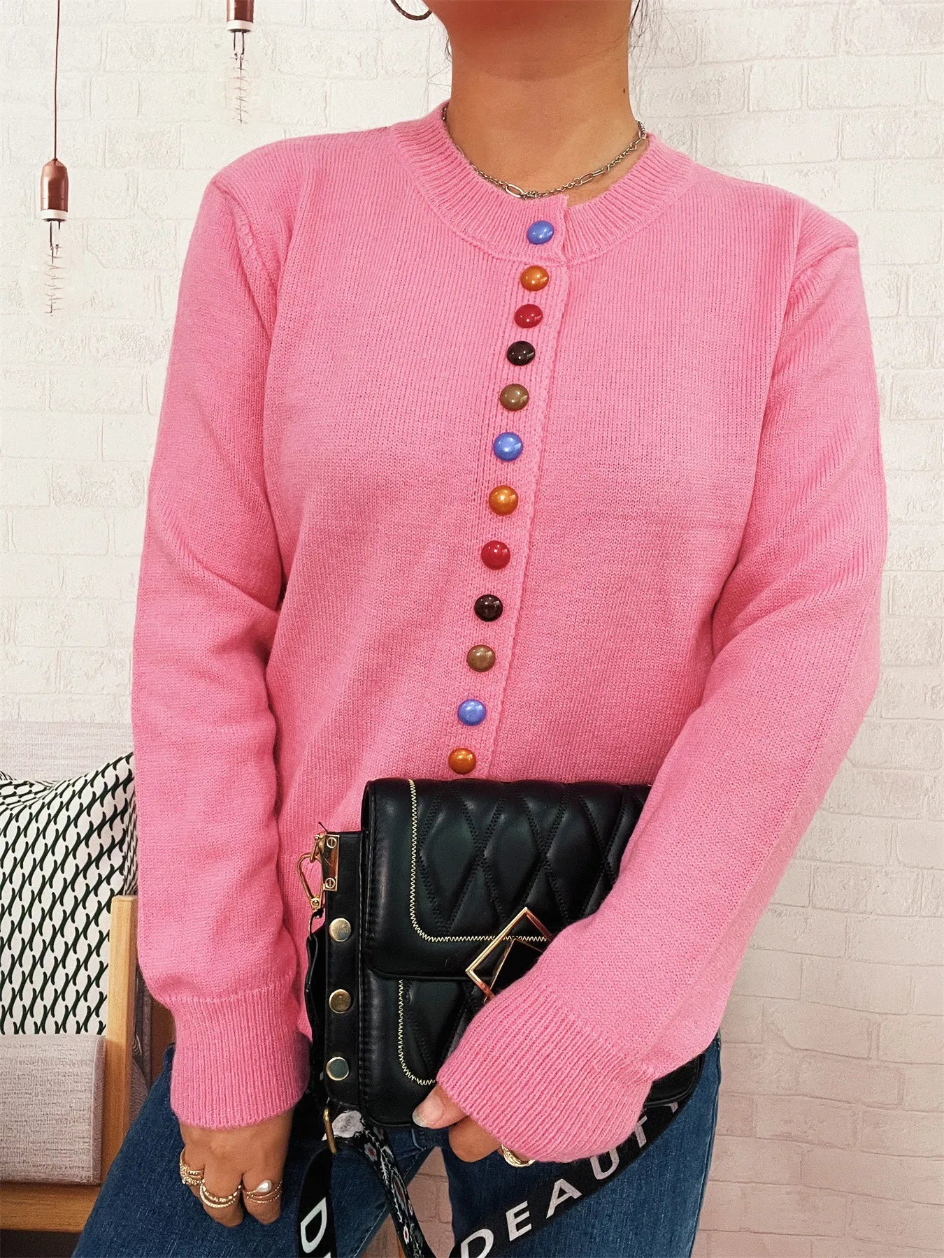 Pink knit cardigan with crew neck and vertical row of multicolor buttons