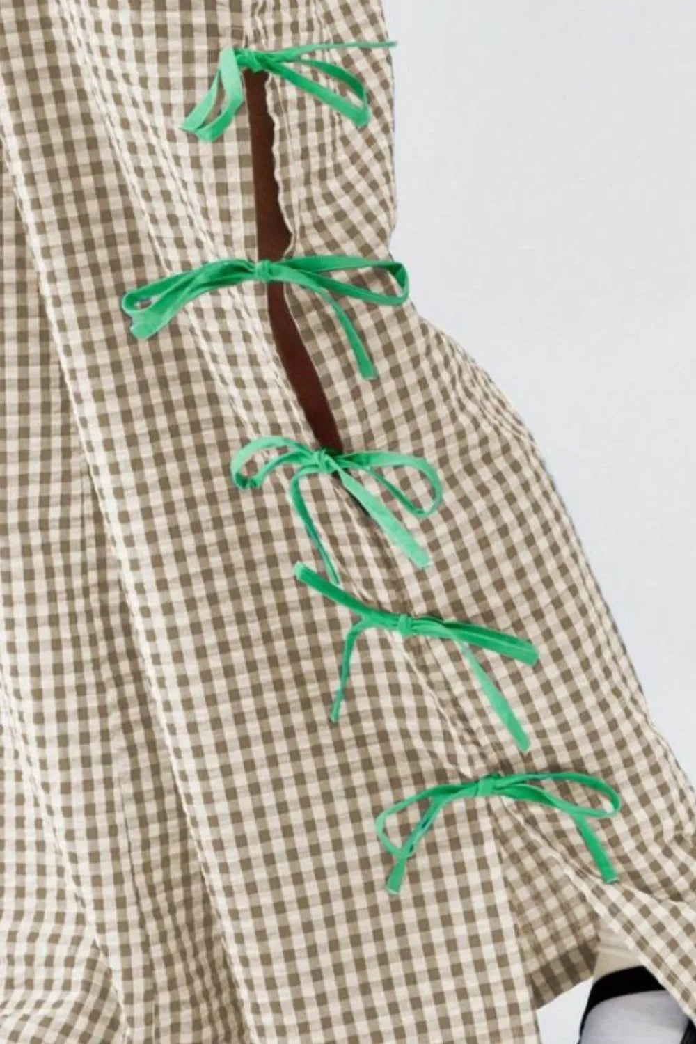 Tan plaid pants with green side ribbon ties, close-up detail