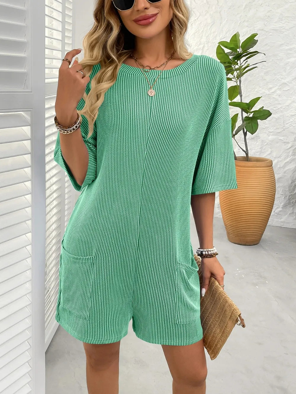 Textured green romper with round neck, half sleeves, and front patch pockets