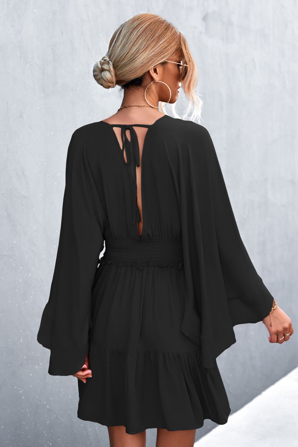Black surplice dress back view with smocked waist and flared sleeves