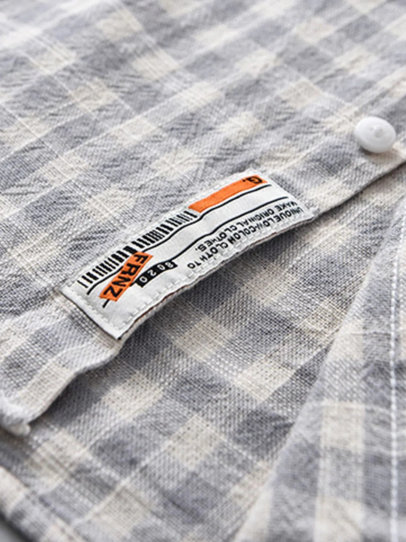 Gray plaid button-up shirt pocket label detail near button placket